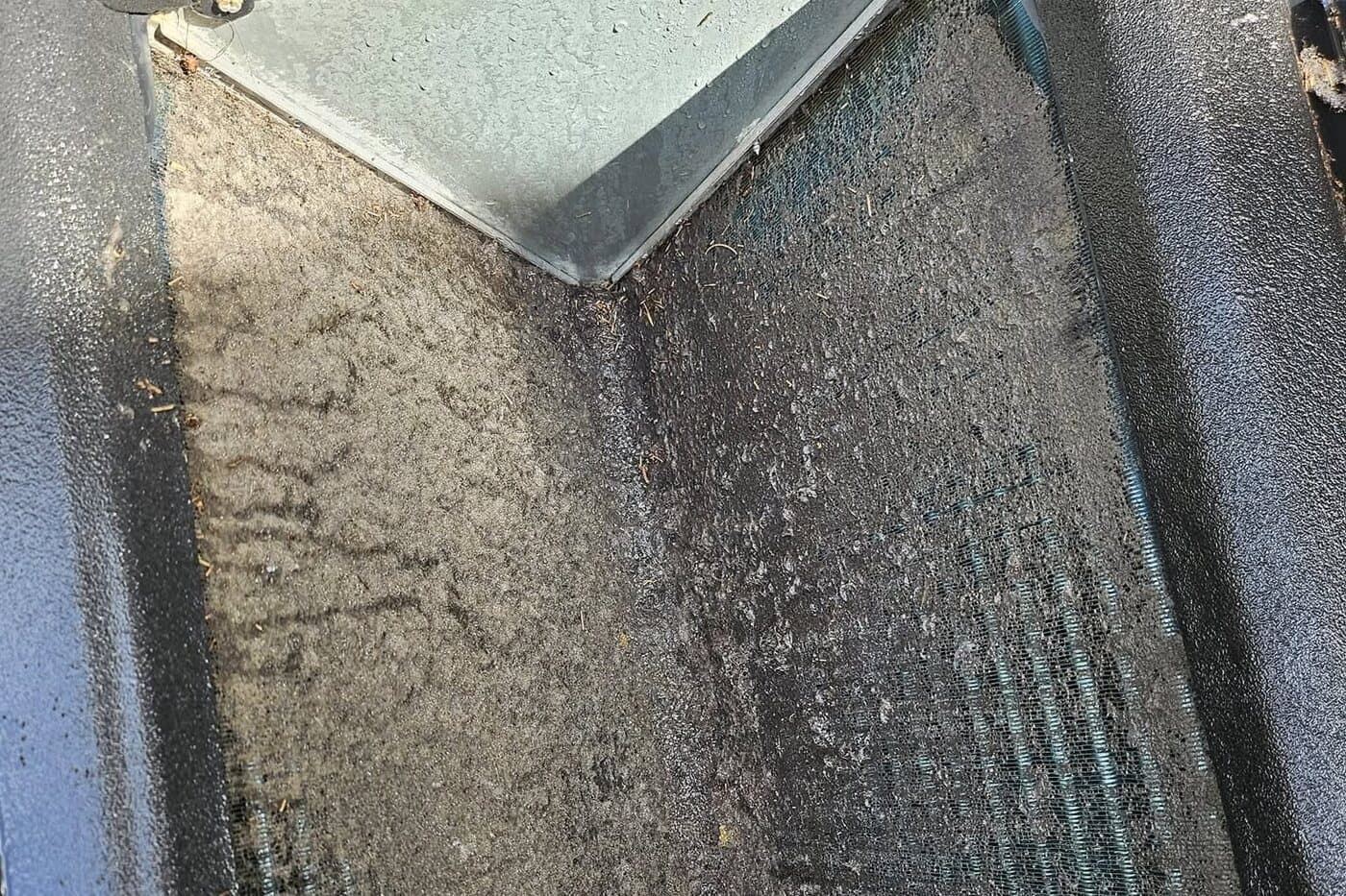 A close-up inside a unit, the pan and its screen buried under a thick mat of dust.